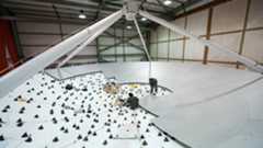 A large antenna dish is half covered by smooth surface panels while the other half is covered by small spikes.