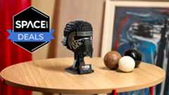 A black brick-built helmet with silver outlines around the eyes is on a display stand on a light brown wooden surface with the space.com logo in the top left corner.