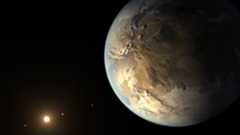 An illustration of exoplanet Kepler 16b, where its brown rocky surface can be seen in the darkness of space with its bright home star far in the distance.
