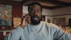 Simon Williams looking shocked as he listens to someone during a mobile phone call in Marvel's Wonder Man