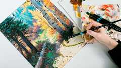 Hand using paintbrush to paint on canvas