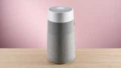 The large Blueair air purifier sits facing forward on a wood surface against a pink background.