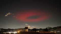 a red halo appears as an eerie symbol in the night sky.
