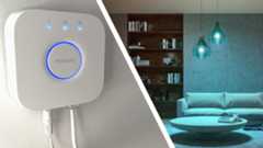 Composite image of Philips Hue Bridge on wall and blue Philips Hue smart lights in living room