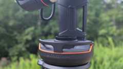 a black and white telescope in a field with trees behind it