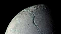A close up of a gray planet with various streaks and ditches in its surface.