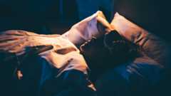 Woman with Insomnia. Young woman lying on bed with hand on forehead.