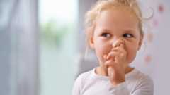 A little girl picking her nose.