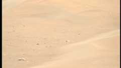 Reddish-tan sand is seen with a few rocks at the base of a large ripple in a photo taken by NASA's Perseverance Mars rover