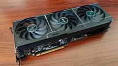 AMD Radeon RX 9070 graphics card lying on woodgrain desk at an angle.