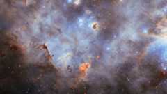 Purple and white clouds of dust and gas swirl around bright twinkling stars in deep space
