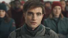 Robert Pattinson sits with a neutral expression in the sunlight in Mickey 17.