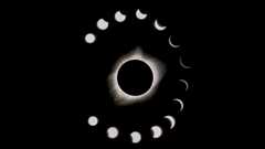 during a total solar eclipse the sun appears as a dark spot with bright white light beaming out from behind. A series of phases surround the main eclipse image, showing the moon take a progressively bigger "bite" out of the sun. 