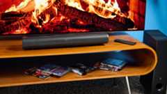 the creative stage pro soundbar and subwoofer, a super-budget home cinema system with 2.1 channels and a remote control photographed on a wooden tv stand with a TV behind