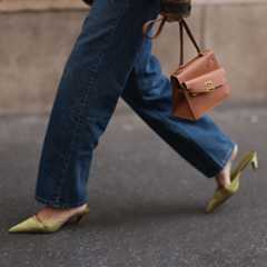 a close up of a woman wearing green everyday heels, jeans and a brown hermes bag