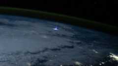 A photo from space showing a giant jet of blue light shooting above a thunderstorm