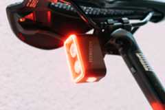 A close up of a rear bike light with two bulbs and one bulb underneath