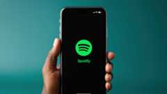 Someone holding an iPhone showing the Spotify app logo