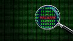 Magnifying glass enlarging the word &#039;malware&#039; in computer machine code