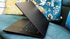 A black ASUS ProArt P16 laptop on a green sofa