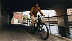 Man cycling under a canal bridge 