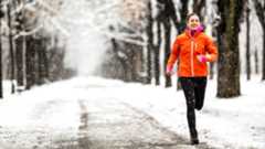 A young woman running in a snowy park 