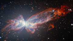 A butterfly shaped nebula of red and white light glows in the darkness of spce