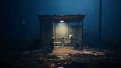 Three figures sit in a bus shelter