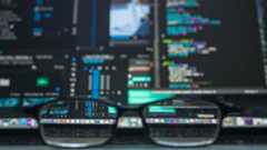 A laptop display with a coding IDE open and spectacles in the front