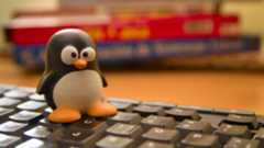 A Tux penguin emblem of the Linux operating system on a computer keyboard