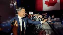 Pierre Polievere in a crowd of people with Canadian flag in the background.