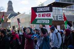 Woman holds a sign saying 'Genocide is never justified' at a rally against the war in Gaza in Toronto.