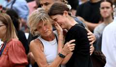 A woman comforts a crying girl amid a crowd of mourners.