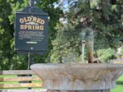 water flowing out of old red spring into its basin with an informational sign in the background