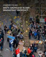 Dieser Alternativtext wurde KI-generiert: Eine Aufnahme von oben zeigt eine belebte Straße mit Fußgängern und Fahrradfahrern. Im Vordergrund sind Straßenschilder und ein Baum zu sehen.