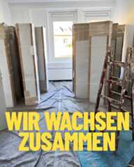 Dieser Alternativtext wurde KI-generiert: Innenraum mit mehreren Kartons und einer Leiter vor einer Tür. Im Vordergrund steht ein Text in großen gelben Buchstaben auf blauem Grund.