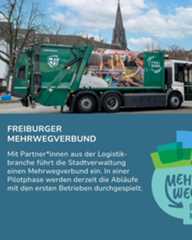 Dieser Alternativtext wurde KI-generiert: Ein großer, grüner Müllwagen steht auf einer Straße. Auf der Seite des Fahrzeugs und auf einem Banner ist Werbung zu sehen.