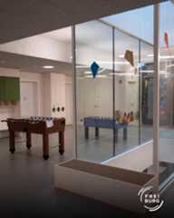 Dieser Alternativtext wurde KI-generiert: Ein heller Raum mit zwei Tischfußballspielen. Durch eine große Glasfront ist ein weiterer Raum mit bunten Dekorationen zu sehen.