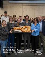 Dieser Alternativtext wurde KI-generiert: Eine Gruppe von Menschen steht zusammen und lächelt in die Kamera. Eine Person hält einen Korb mit Backwaren vor sich.