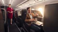 Passenger and cabin crew receiving beverage service in the Business Class cabin