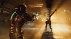 Dead Space remake character with glowing suit aims weapon at creature in a dimly lit Consultation Room. Glen Schofield
