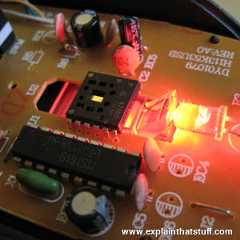 Optical mouse circuit board with red LED light shining through light guide.