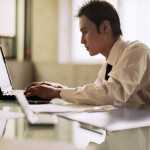 Young man in business shirt works on laptop