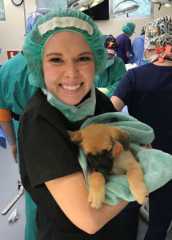 Elizabeth Molinet in scrubs holding a puppy