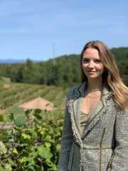 Bethany Rand poses in front of a vineyard