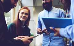 People holding tablets and phones, talking. Photograph.