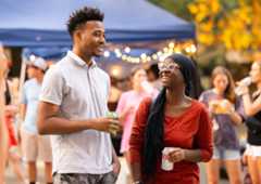 Two students enjoy a conversation at an evening event on campus