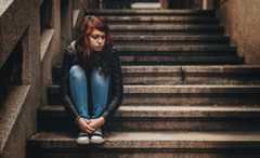 Sad teenage girl sitting on steps alone outside