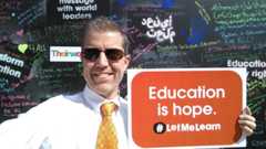 A photo of Dr. Cable Green holding a red sign that says 