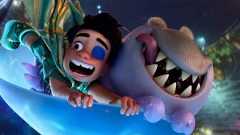 In a still from Disney and Pixar’s Elio, Elio (voiced by Yonas Kibreab), left, and Glordon (voiced by Remy Edgerly), right, are excitedly riding in a light blue cup-shaped vehicle through the Communiverse. They’re holding onto the vehicle for dear life. Elio has a patch over one eye and his mouth is open in a wide smile; Glordon’s tongue is sticking out of one side of his mouth.